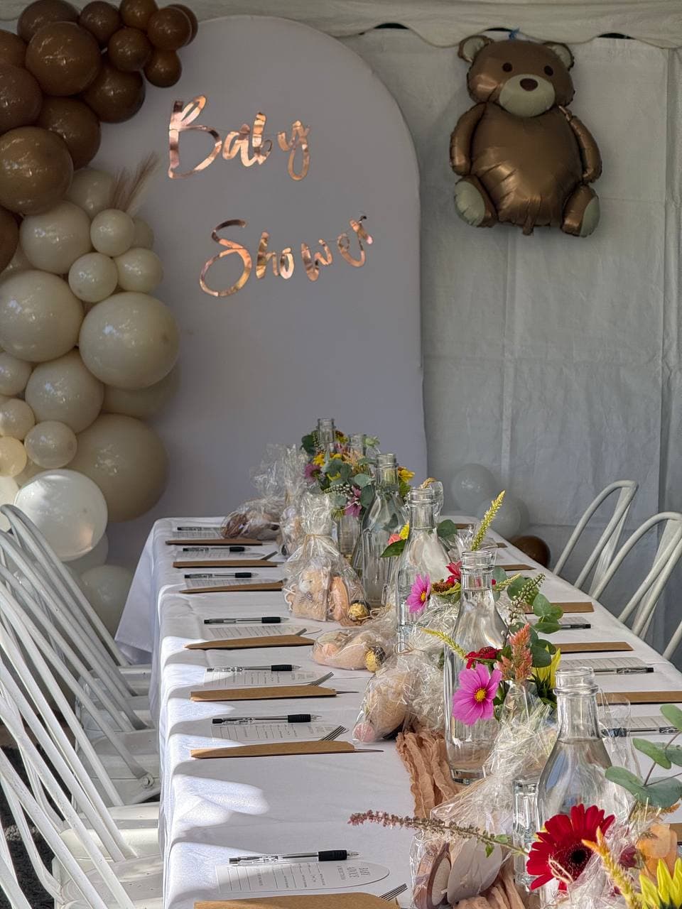 Long baby shower table dressed in white tablecloths with posies and favours at Fairhill, Sunshine Coast