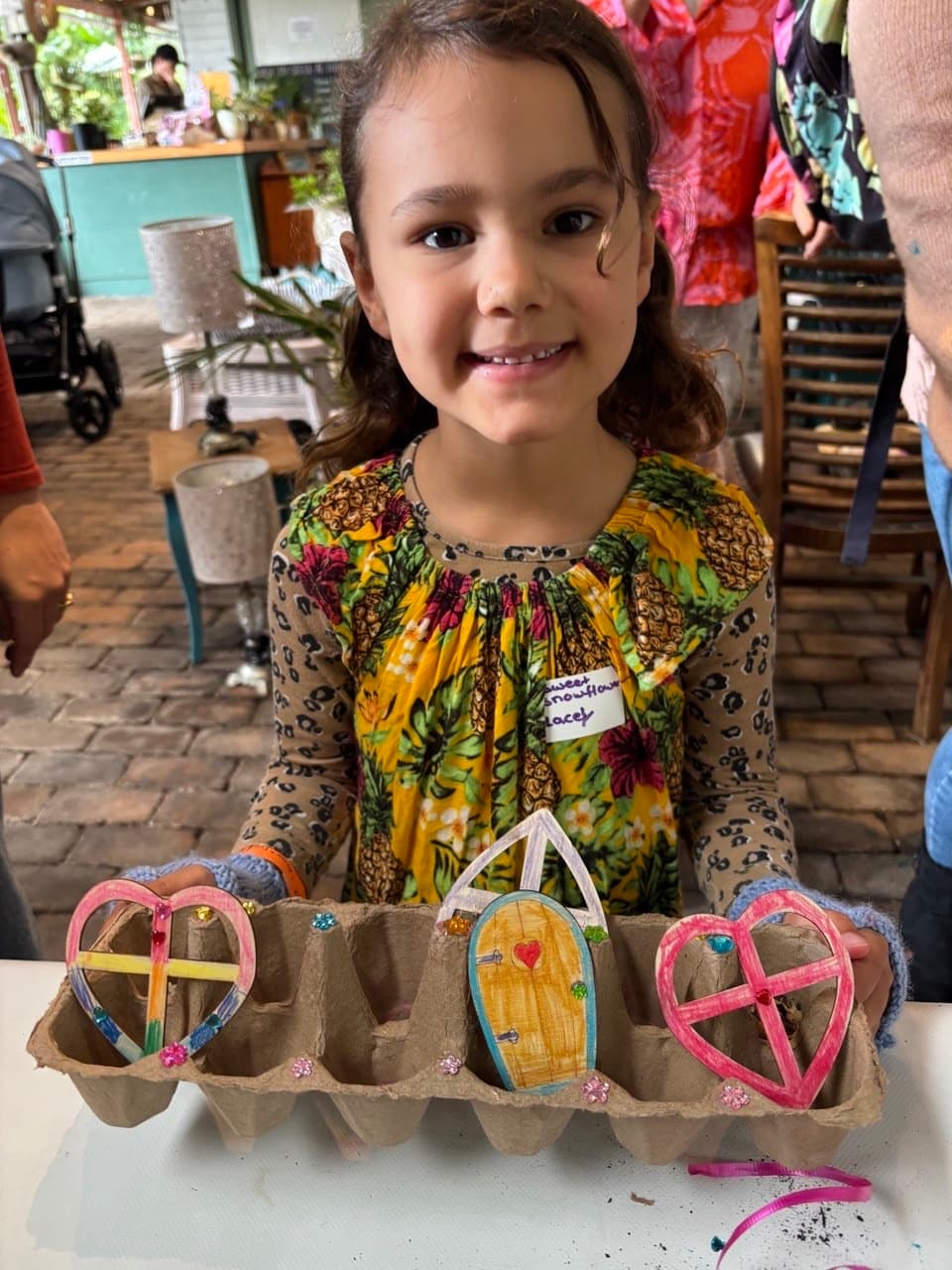 Child holding a handmade nature craft at a Fairhill party