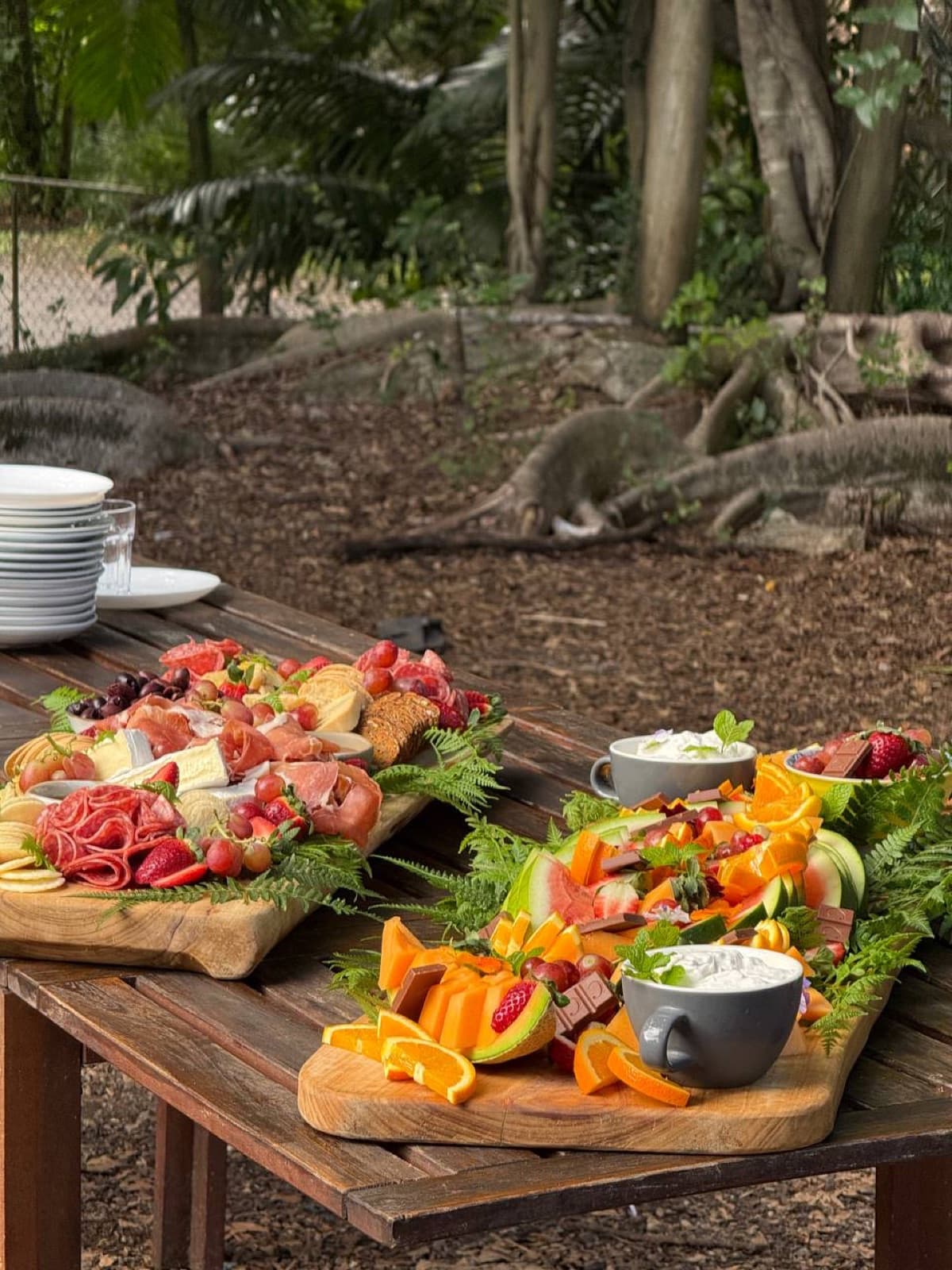 Grazing and fruit platters laid out on a rustic timber table in the Fairhill gardens