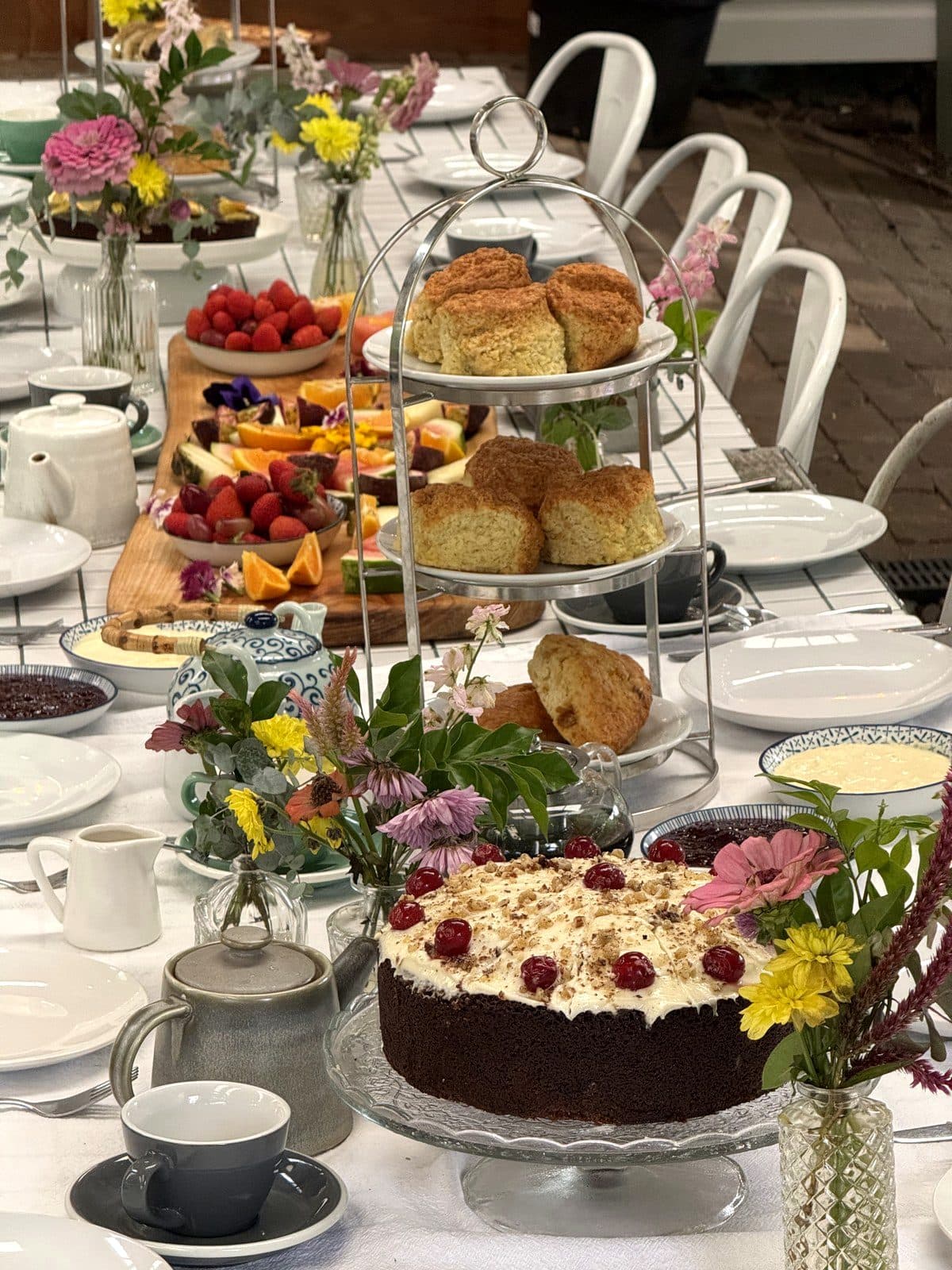 A paddock-to-plate grazing board scattered with edible flowers beside scone stands at the Bush Harvest Morning Tea