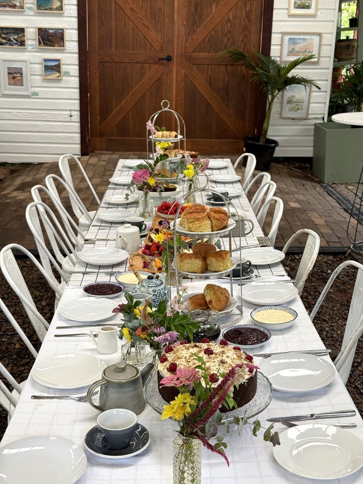 Looking down the Bush Harvest Morning Tea table at Fairhill: tiered stands of scones, grazing boards and posies of garden flowers