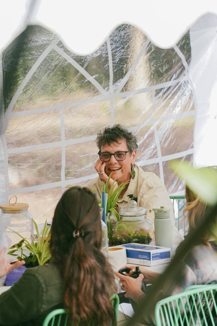 Dr Sarah Pye laughing with workshop guests behind a table of freshly planted terrarium jars