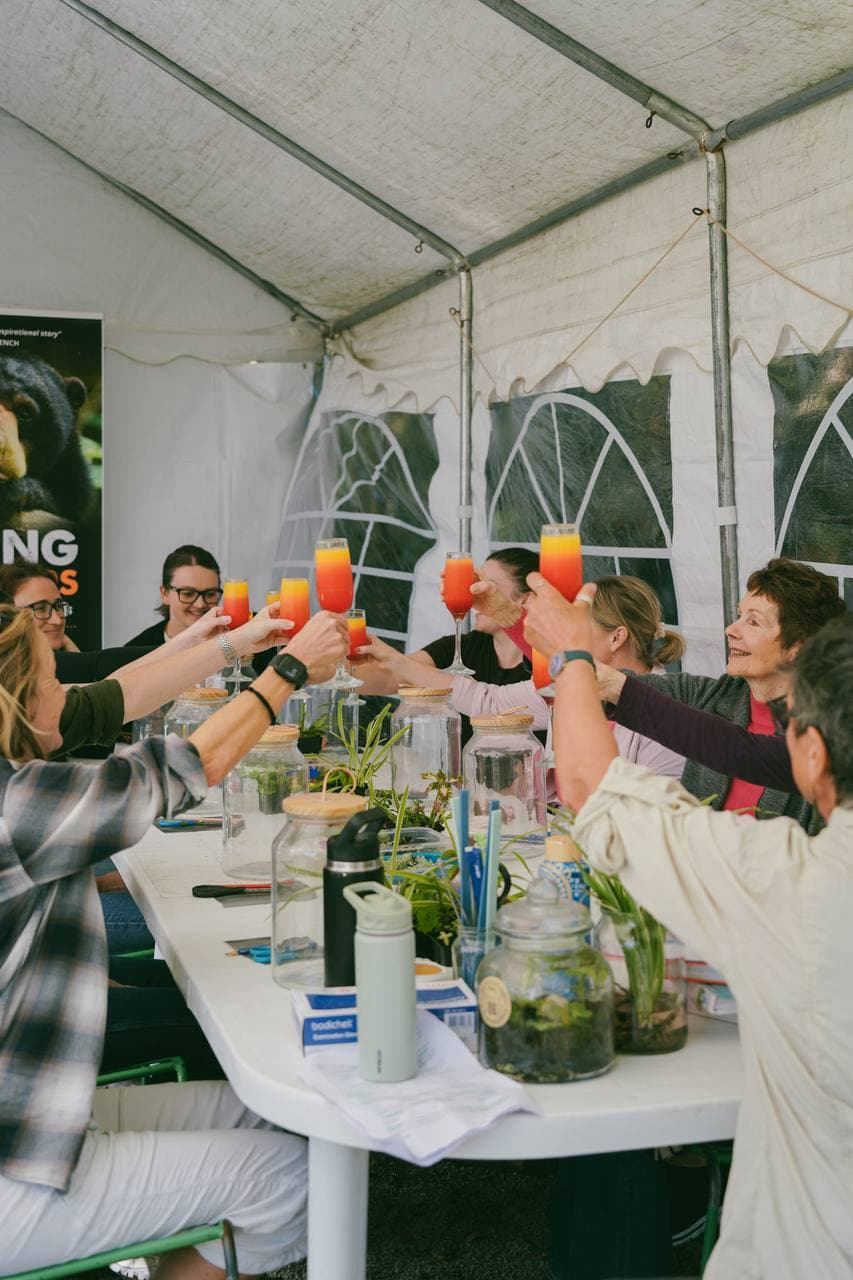The whole workshop table raising sunrise mimosas in a toast under the Fairhill marquee