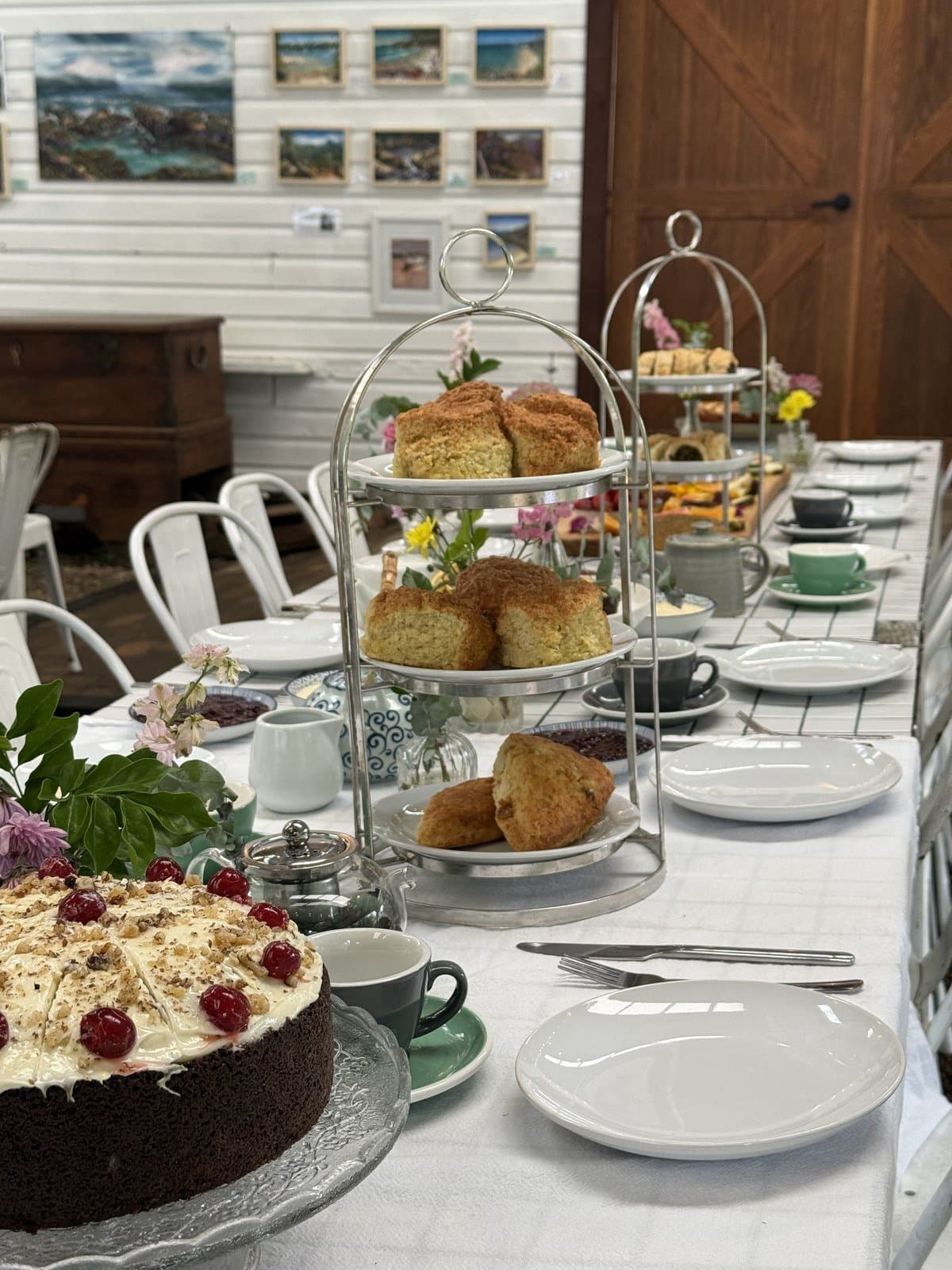 Tiered stands of golden scones beside a frosted cake topped with cherries, set for morning tea in the Fairhill Pavilion
