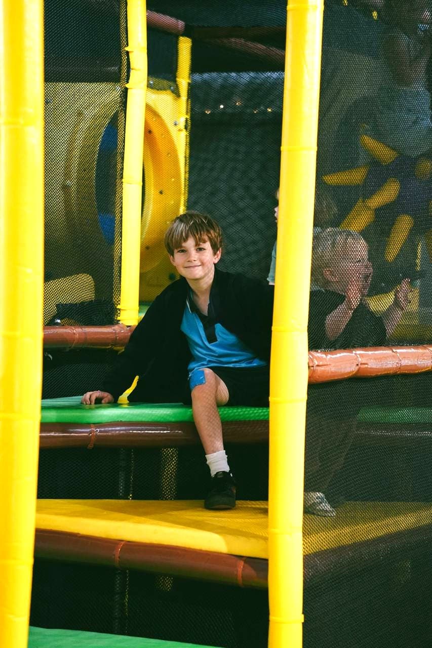 A boy grinning from the climbing tower in Little Sprouts