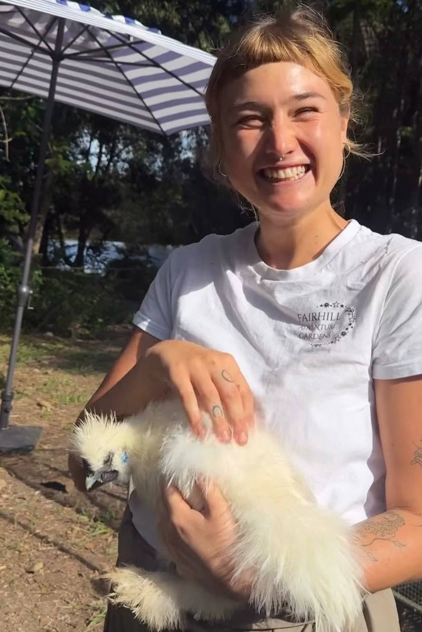 A Fairhill cafe teammate holding a silkie chicken in the gardens