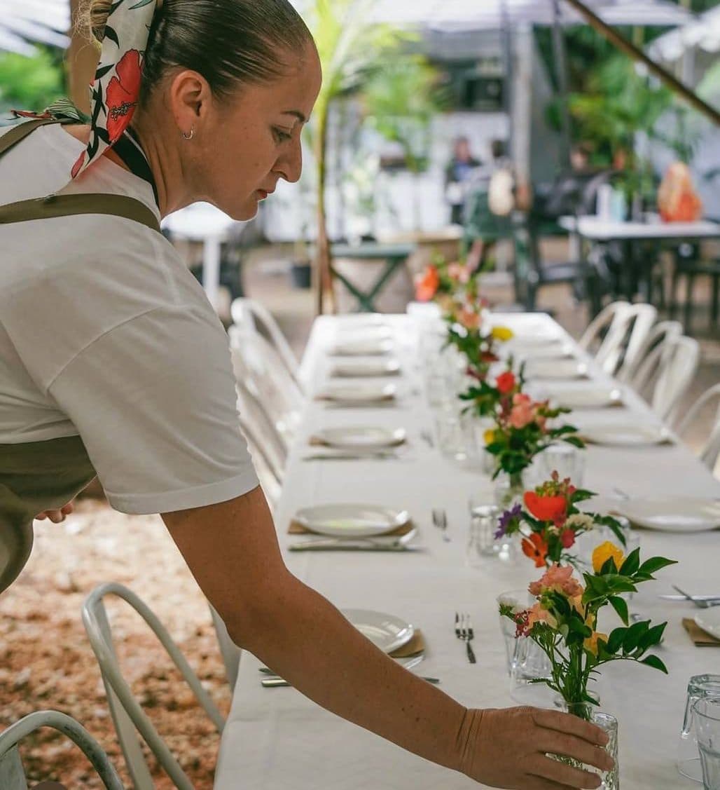 A Fairhill teammate setting the long table under the fig trees for an event