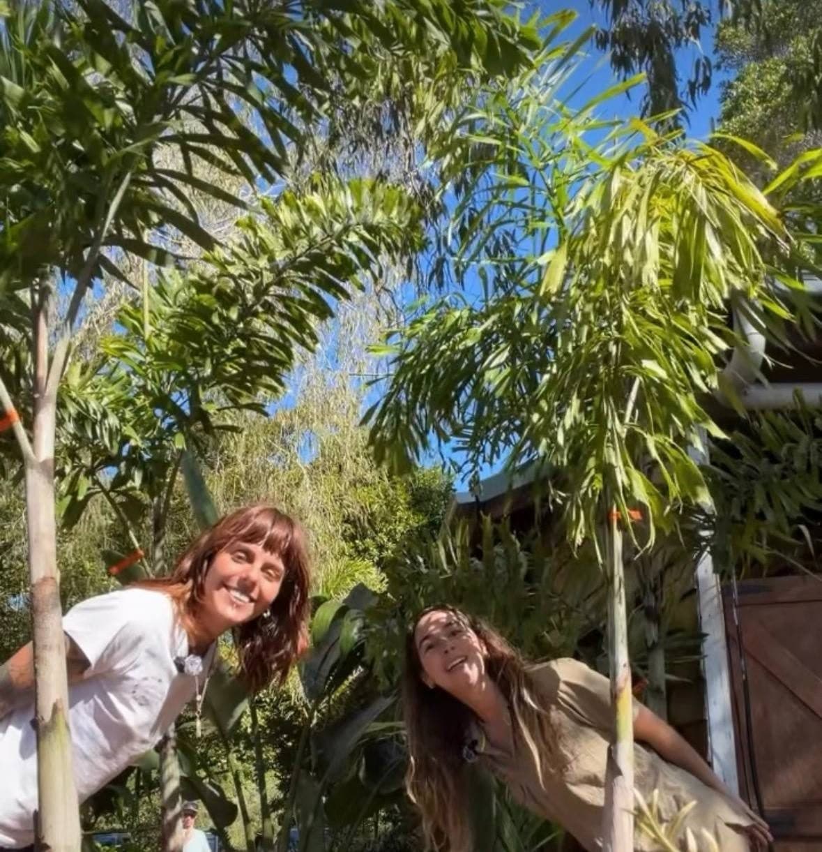 Two Fairhill teammates laughing under the palms on a sunny Sunshine Coast day