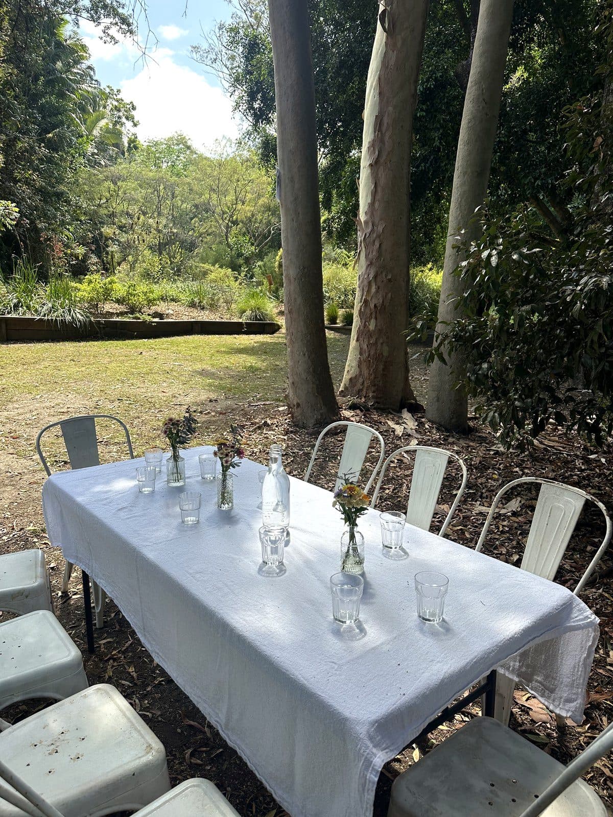 A white-linen long table set for dining among the gum trees at Fairhill